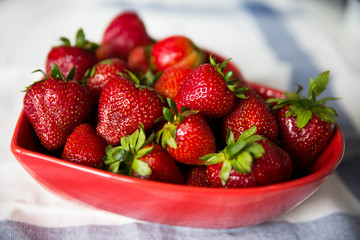 Strawberries in a red heart shaped bowl.