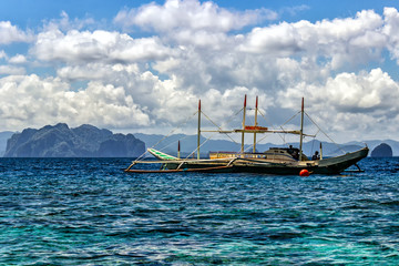 Filipino fishing boat on a background of a cloudy blue sky.
