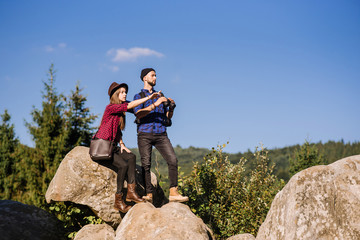 A traveler couple standing together on the rocks at the mountains over the blue sky background