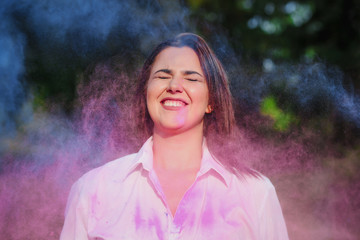 Delightful caucasian model posing with closed eyes with exploding around Holi paint