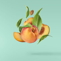 Flying fresh ripe peach with green leaves isolated