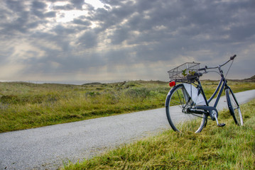 A bicycle on a deserted road under storm clouds