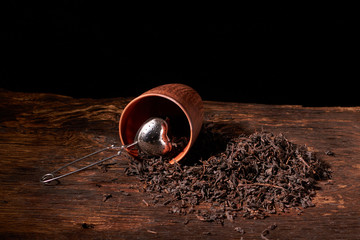 dry black chinese tea set,with strainer closeup,cups and teapot on background over old wood board