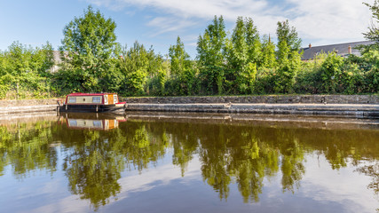 Obraz premium Bridge and barge reflecting in the water of Brecon Canal basin in Brecon, Beacons National Park, Wales, UK