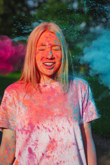 Lovely caucasian woman posing with exploding blue and pink dry Holi paint