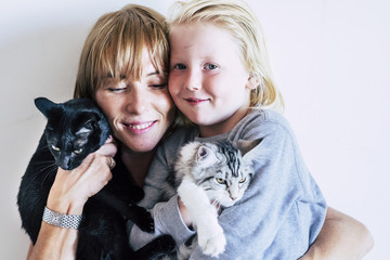family portrait with  caucasian mother blonde beautiful middle age woman and young white skin son and two lovely adorable cats. group hug with persons and animals. best friends forever together