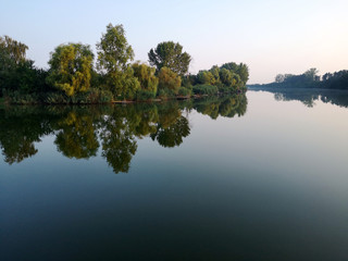 Calm river in beautiful sunrise, green natural lanscape.