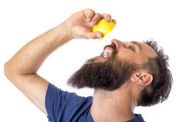 Man with long beard squeeze lemon in his mouth