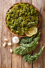 Freshly cooked kale cabbage with onion and garlic and lemon close-up. Vertical top view