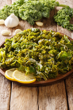 Freshly cooked kale cabbage with onion and garlic and lemon close-up. vertical