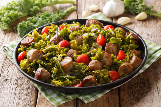 kale with grilled sausages, fresh tomatoes and garlic close-up on a table. horizontal