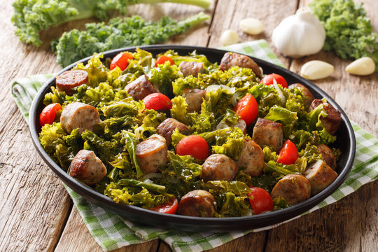 Delicious healthy food: organic kale cabbage with sausages, tomatoes and garlic close-up on a plate. horizontal