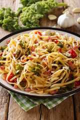 Italian lunch of pasta with cabbage kale, bacon, tomatoes and parmesan closeup. vertical