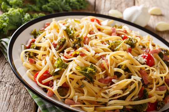 Homemade pasta with fried kale, bacon, tomatoes, garlic and parmesan close-up. horizontal