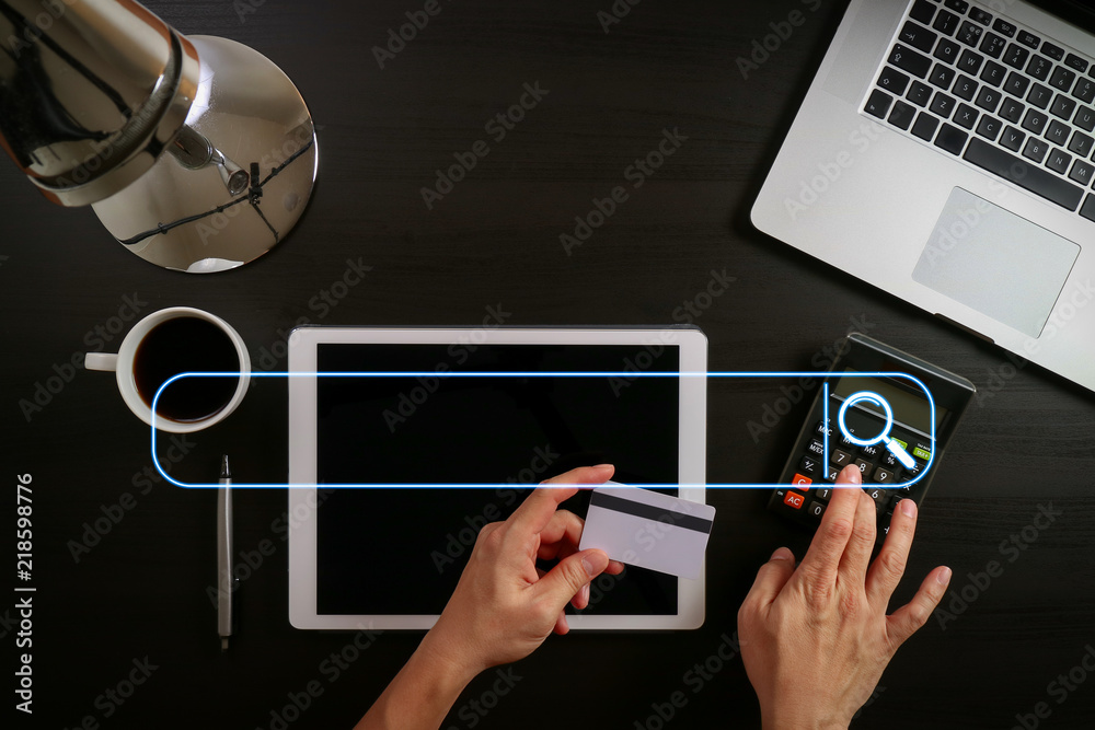 Poster Internet shopping concept.Top view of hands working with laptop and credit card and tablet computer on dark wooden table background
