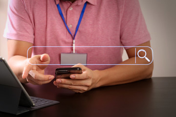 businessman in pink t-shirt working with smart phone and digitl tablet computer on wooden desk in modern office