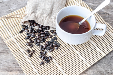 Hot coffee cup with roasted coffee beans on the wooden table
