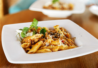 Penne chili con carne - pasta with minced meat, spicy chilli sauce and grated cheese. Shallow focus.