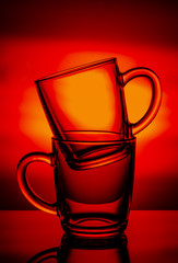 Two glass cups on an red background.