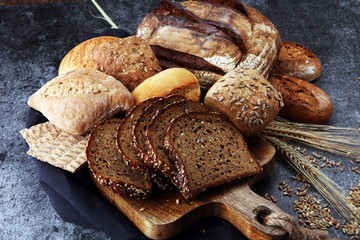 Sliced rye bread on cutting board. Whole grain rye bread and rolls with seeds.