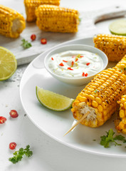 Grilled sweet corn with white mexican sauce, chilli and lime. healthy summer food