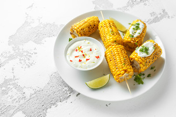 Grilled sweet corn with white mexican sauce, chilli and lime. healthy summer food