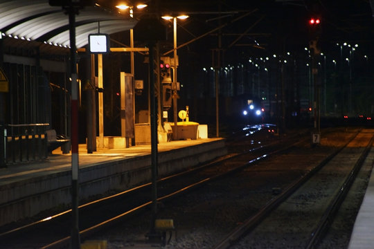 Bahnschienen nachts  / Der Bahnsteig eines Bahnhofes in der Nacht mit einem einfahrenden Zug in der Kurve.