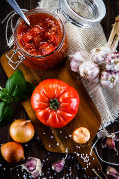 Raw tomatoes and tomato sauce in jar