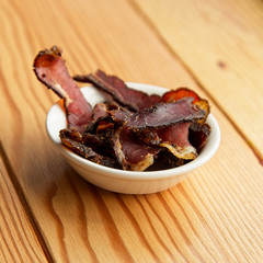 Biltong (dried meat) on a wooden board, this is a traditional food snack that can be found in South...