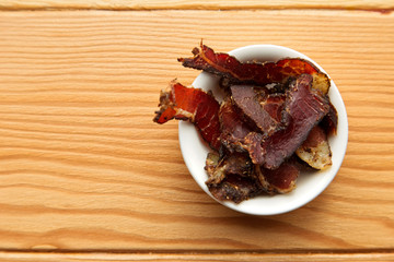 Biltong (dried meat) on a wooden board, this is a traditional food snack that can be found in South Africa.