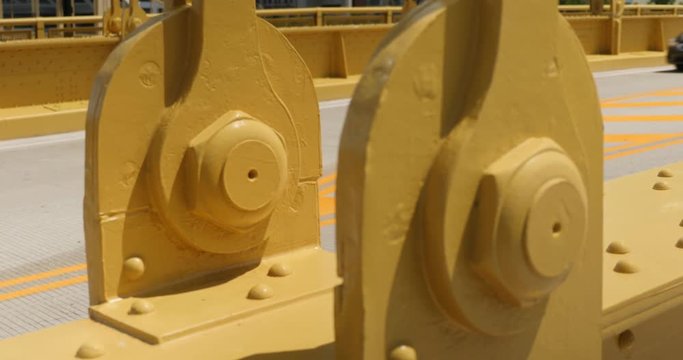 A slow dolly tracking shot of the yellow steel beams on the Andy Warhol Bridge over the Allegheny River in Pittsburgh as traffic passes by.  	