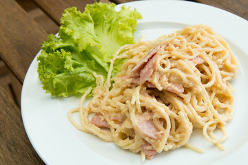 Delicious of Carbonara Spaghetti with ham, bacon and cheese on wood table.
