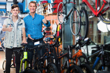 Man and boy holding thumbs up while buying new bicycle