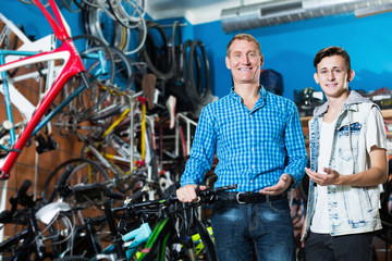 Smiling man and his son teenager buying new bicycle