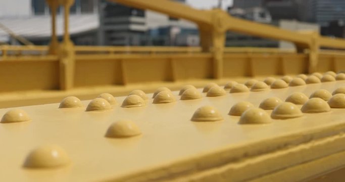 A slow dolly tracking shot of the yellow steel beams on the Andy Warhol Bridge over the Allegheny River in Pittsburgh as traffic passes by.  	