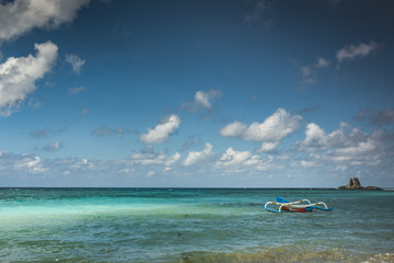 Beautiful beach view in Lombok Island with cloudy blue sky and traditional fishing boat