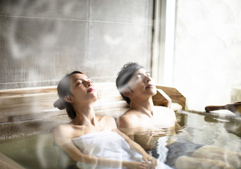 Young couple relaxing in hot springs - obrazy, fototapety, plakaty