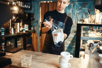 Male barista wipes the dishes after making coffee