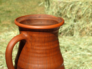 Clay jug on a background of hay bales on a sunny day. Concept for soft drink in hot weather in...