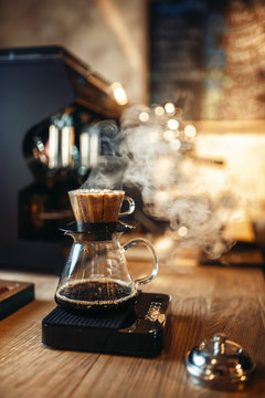 Glass coffee pot with steam on wooden counter
