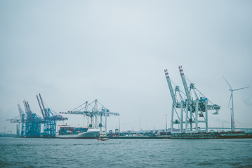 Fototapeta na wymiar Industrial port in Hamburg, Germany. Grey-blue docks in the evening. Dusk covering calm water of the winter sea