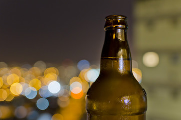 botella de cerveza con fondo de luces de ciudad