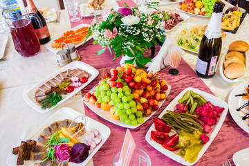 Served table at the Banquet. Fruits, snacks, delicacies and flowers in the restaurant. Solemn event or wedding.