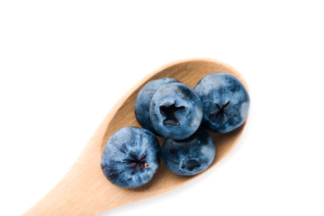 Fresh blueberries in wooden spoon on white background