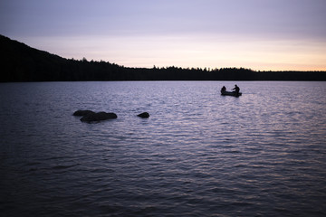 Sunrise over a lake with a couple in a small fishing boat.