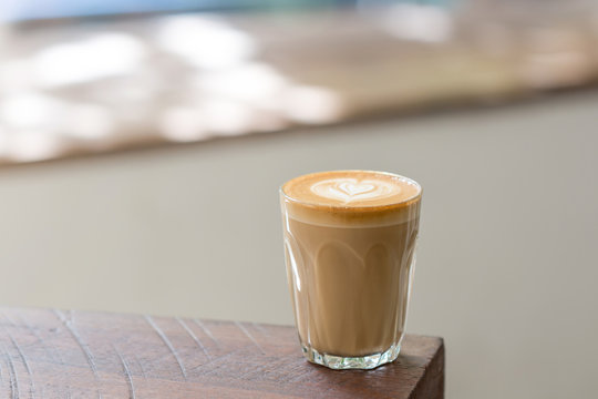 A Cup of Piccolo latte coffee with latte art on the wooden table background.
