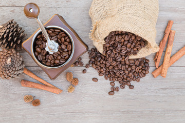 Old Vintage coffee grinder in a wooden case and roasted coffee beans spilling out of the burlap sack bags with cinnamon sticks. Wooden table background. Top view. (Image stacking technique)