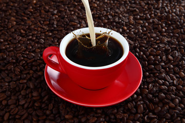 Coffee splash in red cup with coffee beans in background
