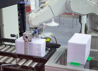 Robot arm loading carton to conveyor in production line. Industrial manufacturing