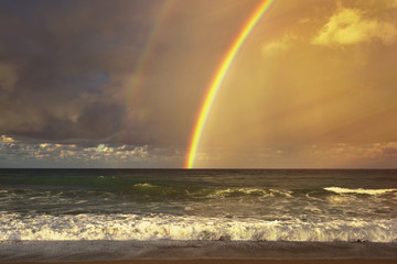 Rainbow over the sea and tropical beach.